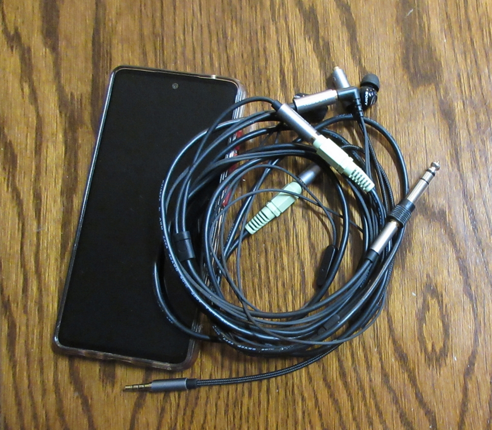 A phone beside a small coil of audio cables